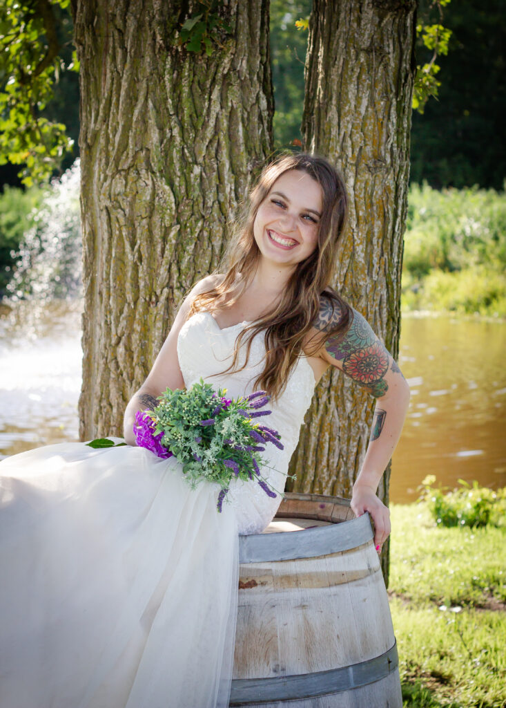 Bride sitting on barrel smiling at Pleasant Pastures Weddings and Events Central Minnesota