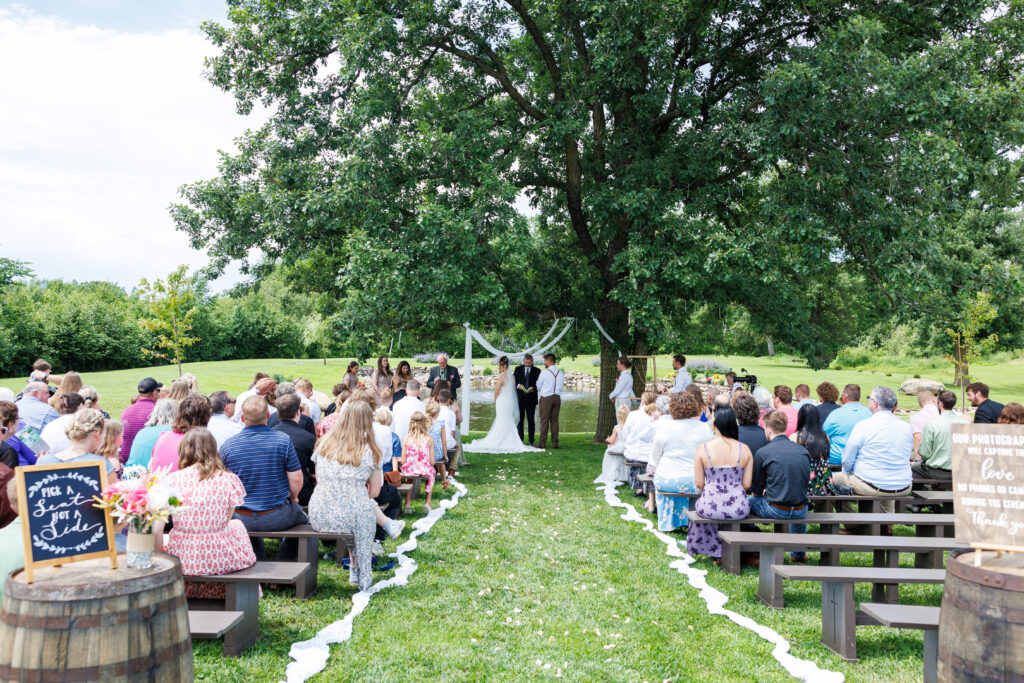 Outdoor wedding venue at Pleasant Pastures Events in Central MN featuring giant oak trees, ponds, outdoor ceremony site, reception tent, concrete dance floor, grain bin bar, garden like setting, rustic outdoor
