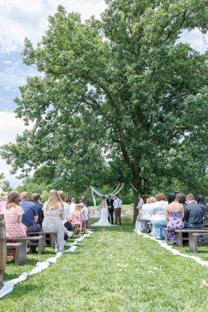 Outdoor wedding venue at Pleasant Pastures Events in Central MN featuring giant oak trees, ponds, outdoor ceremony site, reception tent, concrete dance floor, grain bin bar, garden like setting, rustic outdoor